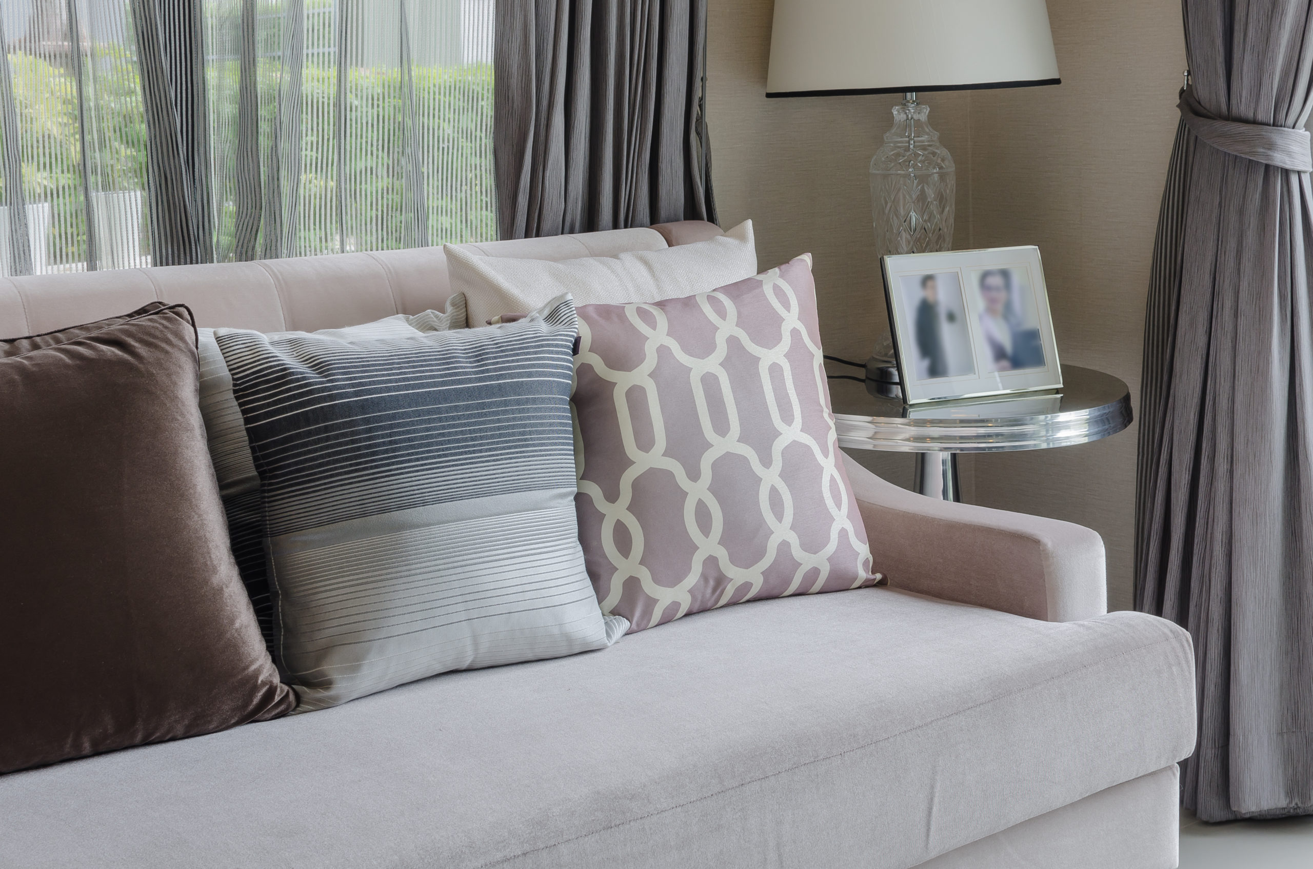 Couch with decorative pillows beside a side table with a lamp and photos in Grimsby, Ontario